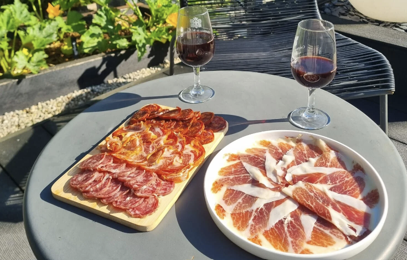 Planche de charcuterie ibérique et assiette de jambon bellota en terrasse avec deux verres de vin rouge