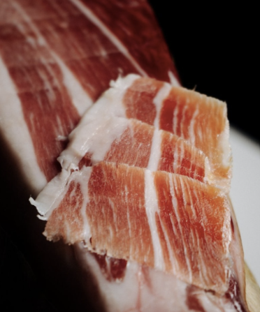 Tranches de jambon ibérique bellota en gros plan, texture marbrée et reflets acajou